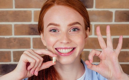 A woman holding an extracted tooth