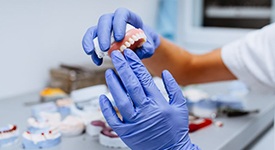 Gloved hands holding denture for upper dental arch