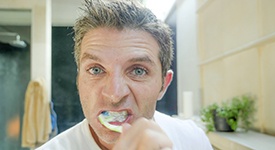 Man brushing his dental implants in San Antonio