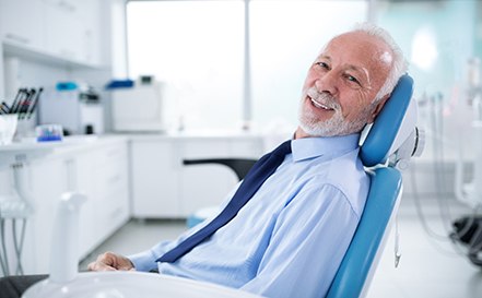 Senior man in tie leaning back in dental chair