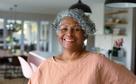 Senior woman standing and smiling at home