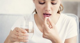 woman taking a pill with a glass of water  