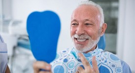 senior man seeing his new smile with dental implants in San Antonio 