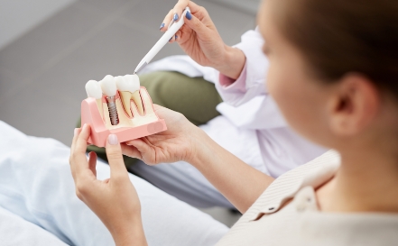 Dentist and patient looking at dental implant tooth replacement model