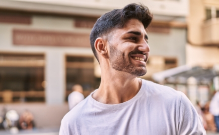 Man with neatly trimmed beard smiling outdoors