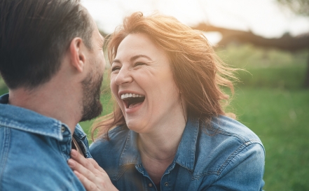 Woman laughing and holding man outdoors