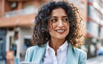 Woman in businesswear smiling on a city street