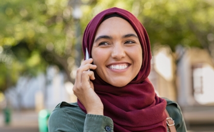 Woman in red headscarf smiling while talking on phone