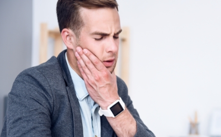 Man holding the side of his jaw in pain