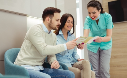 Dental team member and patients discussing dental insurance coverage