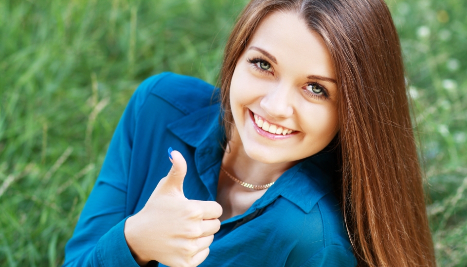 Woman smiling and giving thumbs up after preventive dentistry visit