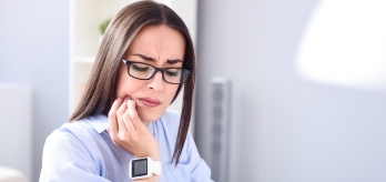 Woman in need of treatment for T M J dysfunction holding jaw in pain