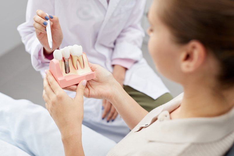 A dentist explaining how dental implants work with a model