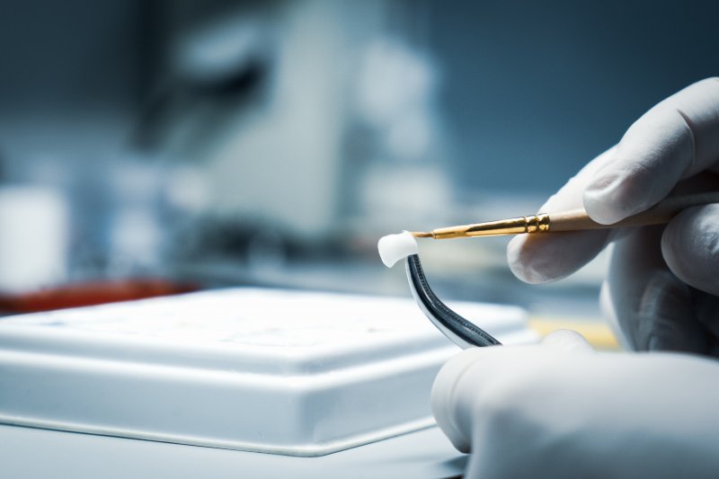 A lab technician processing and correcting a dental crown