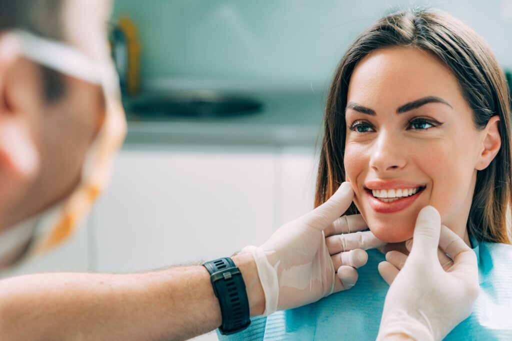 Dentist in gloves touching woman's face